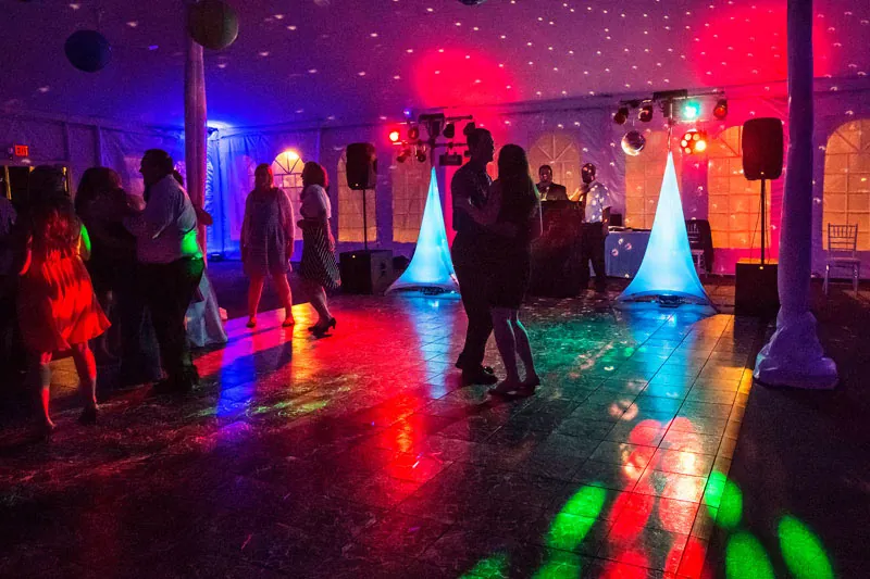 Packed dance floor under colorful uplighting at a Madcap Milwaukee wedding reception
